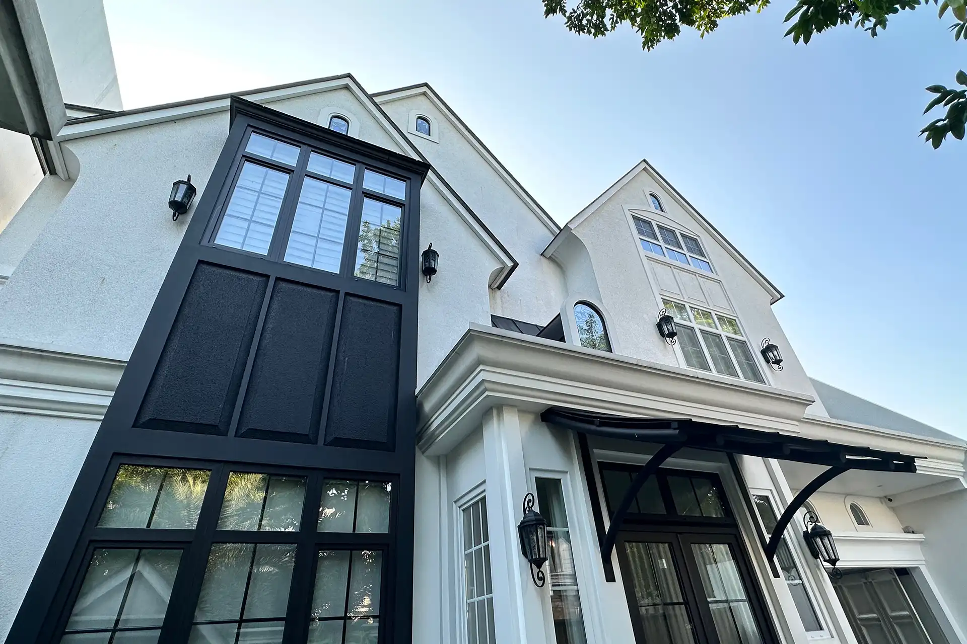 Exterior view of an exclusive private residence in Kebayoran Lama, South Jakarta featuring black and white UPVC windows with internal muntins and a matching entrance door.